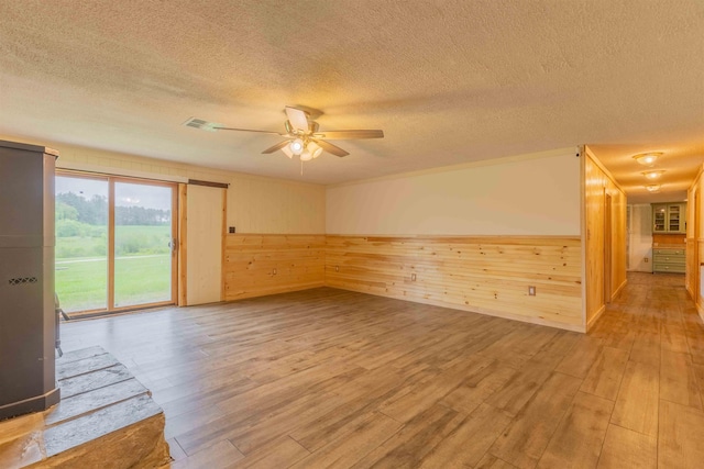 122 Flagg Rd, Rochester, NH 03839 - empty room with a textured ceiling, light wood-style floors, a ceiling fan, and wooden walls