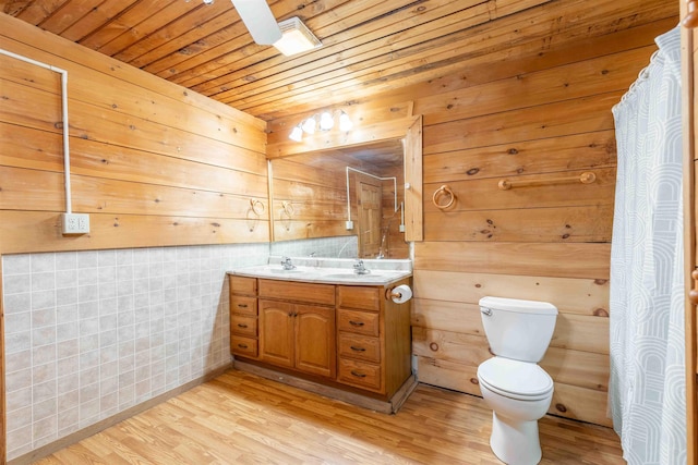 122 Flagg Rd, Rochester, NH 03839 - bathroom featuring double vanity, wood finished floors, toilet, wood ceiling, and wooden walls