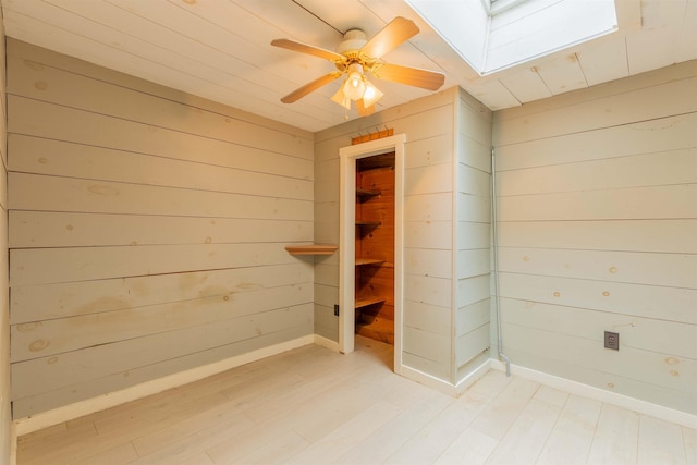 122 Flagg Rd, Rochester, NH 03839 - spare room featuring a skylight, wood walls, light wood-style flooring, ceiling fan, and baseboards