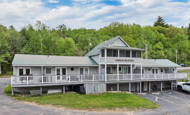 1144 Weirs Blvd Unit 20, Laconia, NH 03246 - view of front of home with metal roof, a front lawn, uncovered parking, and a wooded view