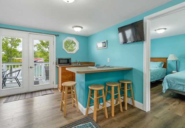 1144 Weirs Blvd Unit 20, Laconia, NH 03246 - kitchen with stainless steel microwave, wood finished floors, a sink, a kitchen breakfast bar, and a peninsula