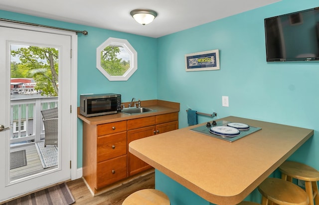 1144 Weirs Blvd Unit 20, Laconia, NH 03246 - kitchen with stainless steel microwave, a sink, brown cabinets, wood finished floors, and a kitchen breakfast bar