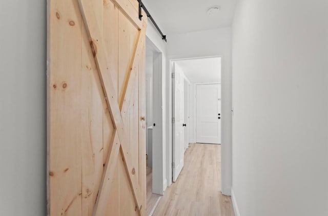 70 Broadway Dr, Amherst, NH 03031 - hallway featuring light wood-style floors, a barn door, and baseboards