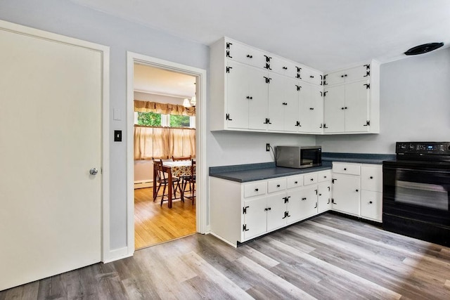 47 Dell Rd, Springfield, VT 05156 - kitchen with black / electric stove, stainless steel microwave, dark countertops, wood finished floors, and white cabinetry