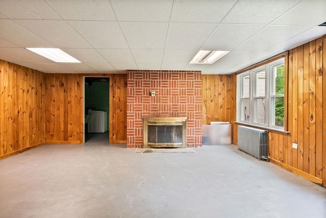 47 Dell Rd, Springfield, VT 05156 - unfurnished living room with radiator heating unit, wooden walls, a brick fireplace, concrete flooring, and baseboards