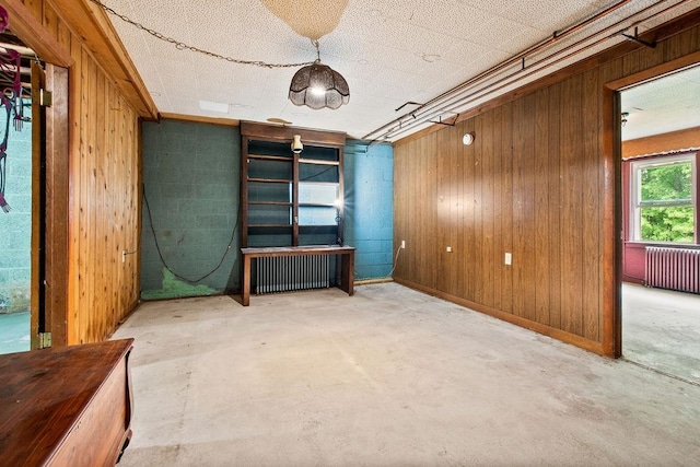 47 Dell Rd, Springfield, VT 05156 - empty room with concrete flooring, radiator heating unit, and wooden walls
