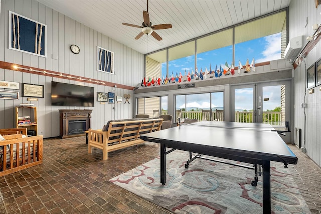 375 Endicott N St Unit 103, Laconia, NH 03246 - rec room featuring a high ceiling, a fireplace, a ceiling fan, brick flooring, and wood walls