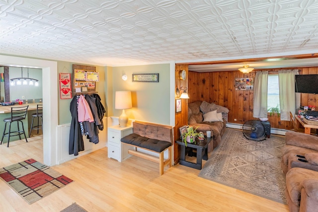 95 Main St, Wells River, VT 05081 - living room featuring wood finished floors, an ornate ceiling, a baseboard radiator, and wood walls