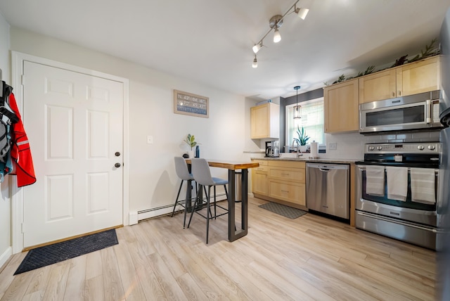 205 Circle Rd Unit 2, Manchester, NH 03103 - kitchen with appliances with stainless steel finishes, light brown cabinets, a baseboard heating unit, and light wood finished floors
