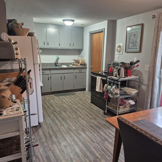 16 Oakwood Dr Unit 16, Claremont, NH 03743 - kitchen featuring stainless steel range with electric cooktop, a sink, freestanding refrigerator, a textured ceiling, and dark carpet
