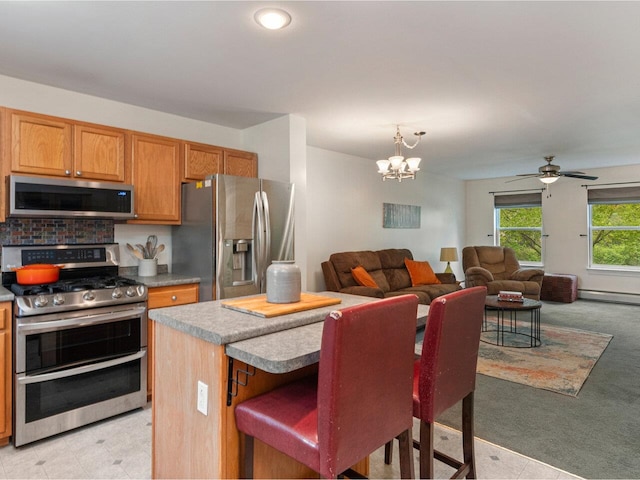 8 Checkerberry Sq Unit 106, Milton, VT 05468 - kitchen featuring appliances with stainless steel finishes, a chandelier, a kitchen island, light carpet, and ceiling fan