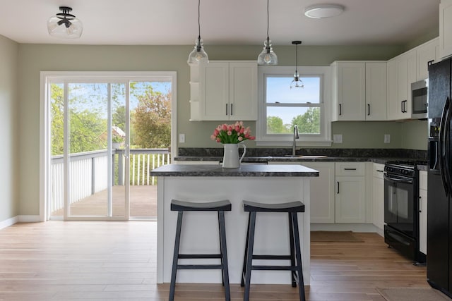 82 Stirrup Cir, Williston, VT 05495 - kitchen with black appliances, a sink, a center island, light wood-style floors, and white cabinets