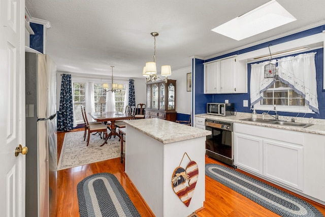 26 Birch Hill Estates Rd, Wolfeboro, NH 03894 - kitchen with a sink, stainless steel appliances, wood finished floors, a kitchen island, and white cabinetry