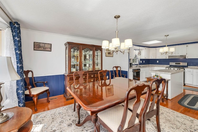 26 Birch Hill Estates Rd, Wolfeboro, NH 03894 - dining area featuring a chandelier, light wood-style flooring, a wainscoted wall, and a textured ceiling