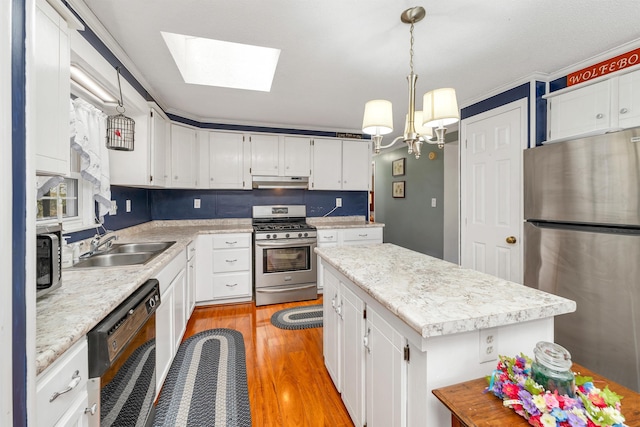 26 Birch Hill Estates Rd, Wolfeboro, NH 03894 - kitchen featuring appliances with stainless steel finishes, under cabinet range hood, light wood finished floors, a center island, and light countertops