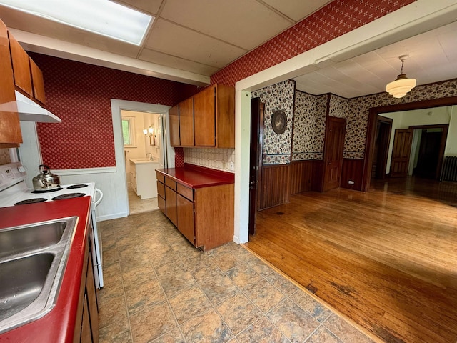 927 Water St, Bennington, VT 05257 - kitchen featuring wallpapered walls, brown cabinets, under cabinet range hood, wainscoting, and electric range