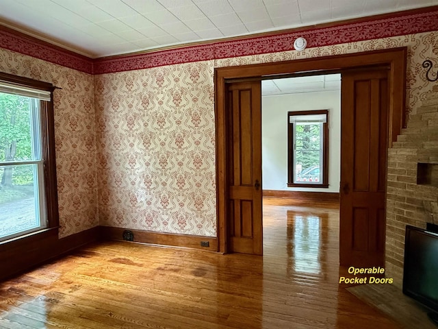 927 Water St, Bennington, VT 05257 - unfurnished room featuring wood-type flooring, healthy amount of natural light, wallpapered walls, baseboards, and crown molding