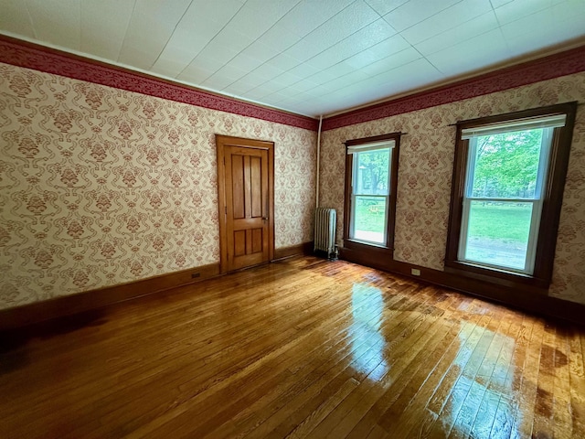 927 Water St, Bennington, VT 05257 - unfurnished room featuring radiator heating unit, wood-type flooring, wallpapered walls, baseboards, and crown molding
