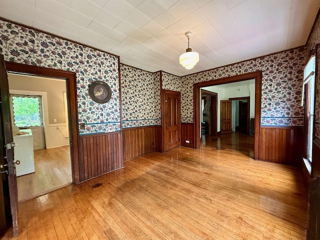 927 Water St, Bennington, VT 05257 - empty room featuring light wood-style floors, wallpapered walls, a wainscoted wall, and washer / dryer