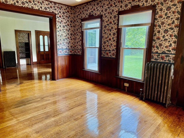 927 Water St, Bennington, VT 05257 - unfurnished room with radiator, hardwood / wood-style floors, wainscoting, wallpapered walls, and crown molding