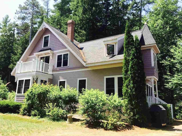 34 Baker Ave, Deerfield, NH 03037 - rear view of house featuring a balcony, a chimney, and view of wooded area