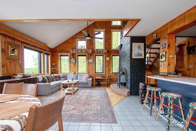 304 Green Bay Loop, Peacham, VT 05862 - living room featuring wooden walls, light tile patterned floors, ceiling fan, a wood stove, and lofted ceiling