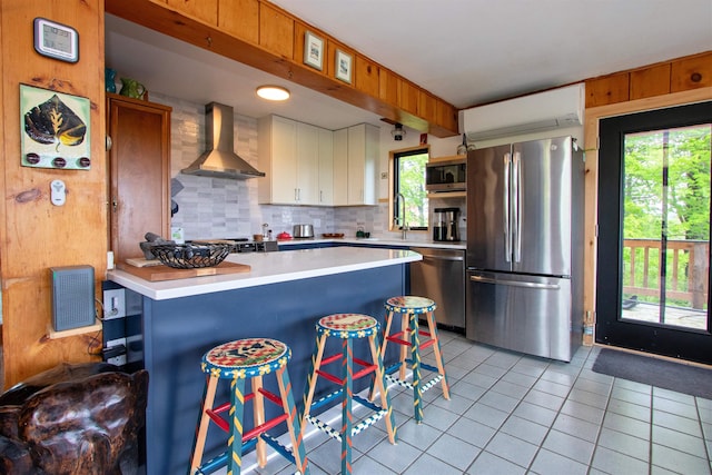 304 Green Bay Loop, Peacham, VT 05862 - kitchen featuring appliances with stainless steel finishes, wall chimney range hood, light countertops, light tile patterned floors, and backsplash