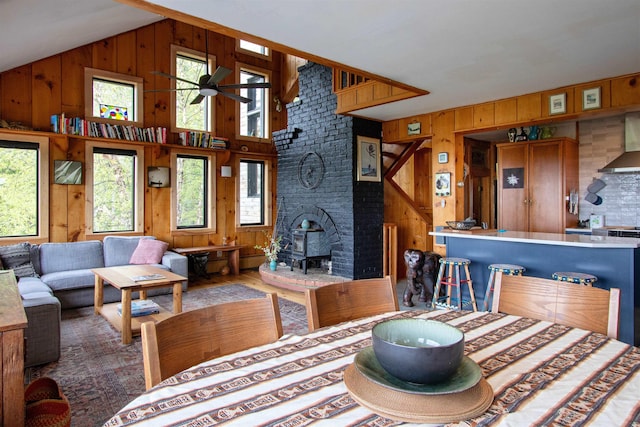 304 Green Bay Loop, Peacham, VT 05862 - living room with wood walls, vaulted ceiling, wood finished floors, a ceiling fan, and a wood stove
