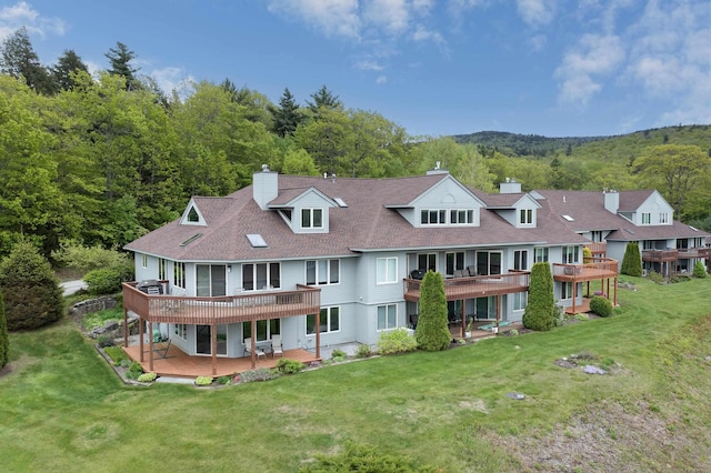 24 N Peak Vlg, Newbury, NH 03255 - back of house with a chimney, a wooden deck, a yard, and a view of trees