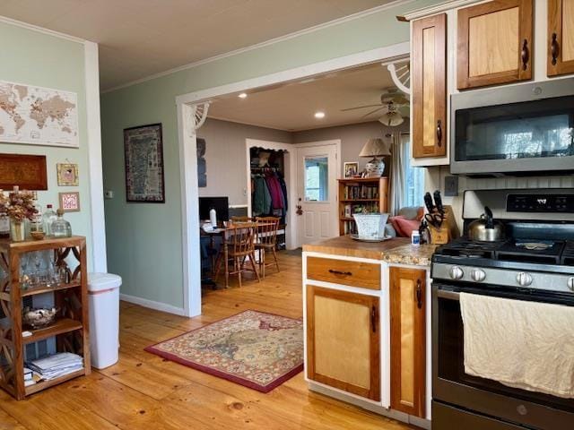 261 Vt 15 E Rd, Hyde Park, VT 05655 - kitchen with appliances with stainless steel finishes, light wood-style flooring, a ceiling fan, crown molding, and light countertops