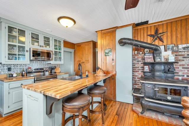 959 Presidential Hwy, Jefferson, NH 03583 - kitchen with stainless steel appliances, a sink, wooden counters, a wood stove, and light wood-style floors