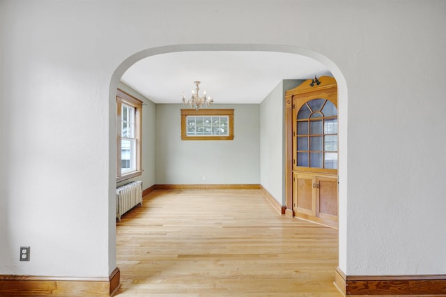 55 Washington St, Rochester, NH 03867 - unfurnished dining area featuring radiator, arched walkways, light wood finished floors, and a chandelier