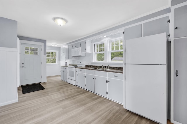 55 Washington St, Rochester, NH 03867 - kitchen featuring white appliances, a sink, dark countertops, light wood-style floors, and plenty of natural light