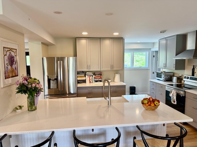 2366 Mountain Rd Unit 3, Stowe, VT 05672 - kitchen featuring appliances with stainless steel finishes, wall chimney range hood, gray cabinetry, a sink, and a kitchen bar
