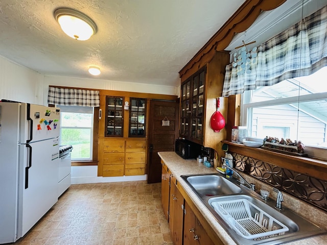 6998 River Rd, Lemington, VT 05903 - kitchen featuring white appliances, a sink, glass insert cabinets, a textured ceiling, and brown cabinets