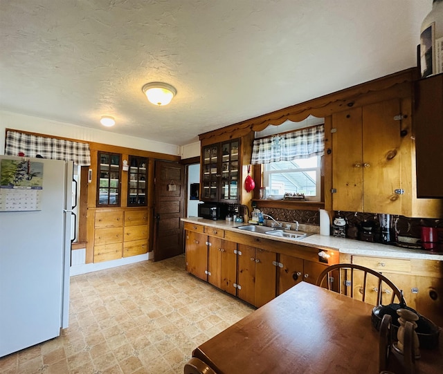 6998 River Rd, Lemington, VT 05903 - kitchen with freestanding refrigerator, a sink, light countertops, brown cabinets, and a textured ceiling
