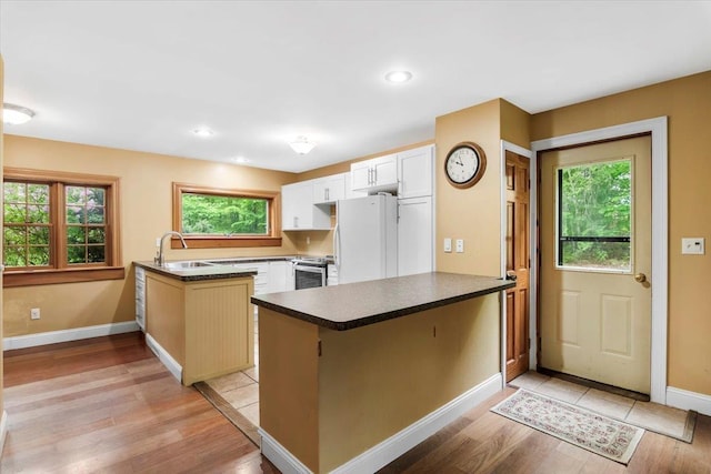 379 Swallow Hill Rd, Pownal, VT 05261 - kitchen featuring a peninsula, freestanding refrigerator, stainless steel range with electric cooktop, dark countertops, and light wood-type flooring