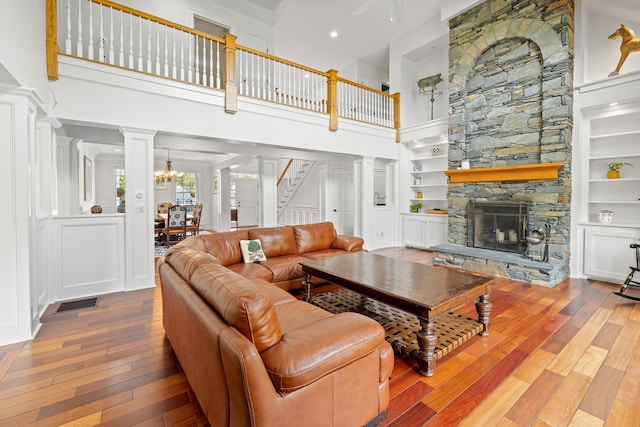 543 Lower Hollow Rd, Dorset, VT 05251 - living area featuring hardwood / wood-style floors, a fireplace, stairs, a towering ceiling, and decorative columns