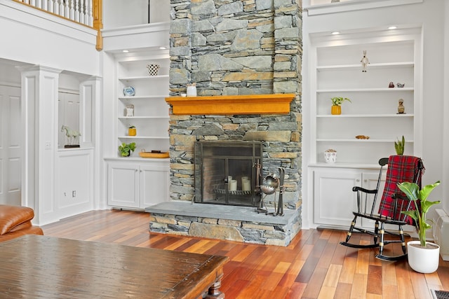 543 Lower Hollow Rd, Dorset, VT 05251 - living area with wood finished floors, built in shelves, a stone fireplace, and ornate columns