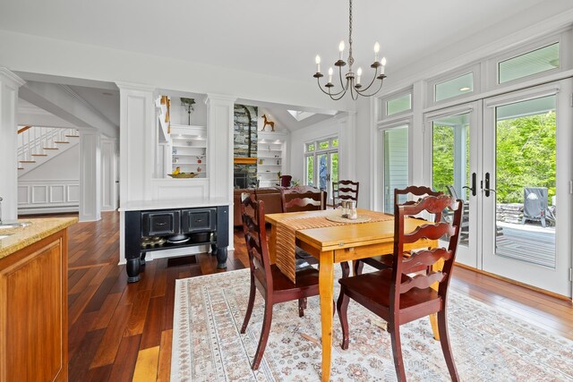 543 Lower Hollow Rd, Dorset, VT 05251 - dining area featuring dark wood finished floors, stairs, french doors, ornate columns, and a chandelier
