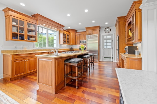 543 Lower Hollow Rd, Dorset, VT 05251 - kitchen featuring appliances with stainless steel finishes, a sink, light wood-type flooring, a kitchen island with sink, and a kitchen breakfast bar