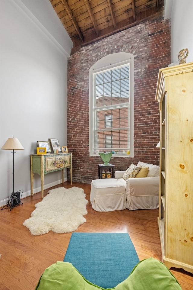 48 Landing Ln Unit 15, Laconia, NH 03246 - sitting room with wooden ceiling with exposed beams, brick wall, wood finished floors, and high vaulted ceiling