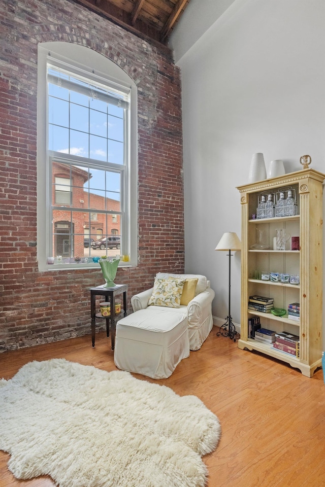 48 Landing Ln Unit 15, Laconia, NH 03246 - living area with brick wall, wood finished floors, a towering ceiling, and beamed ceiling
