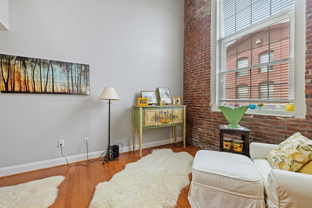 48 Landing Ln Unit 15, Laconia, NH 03246 - sitting room with baseboards, wood finished floors, a high ceiling, and brick wall