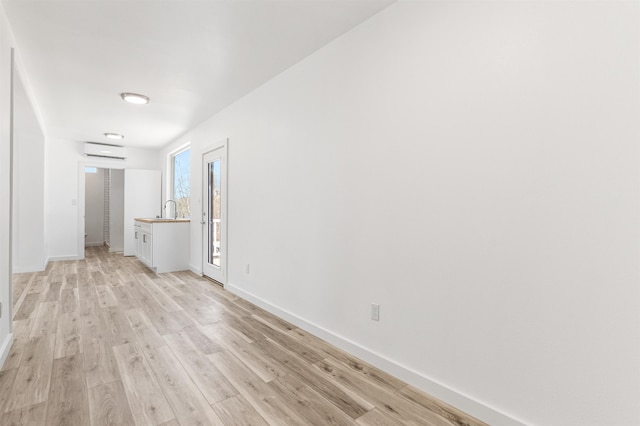 15 Highland Ave, Claremont, NH 03743 - unfurnished room featuring a wall mounted air conditioner, baseboards, light wood-style floors, and a sink