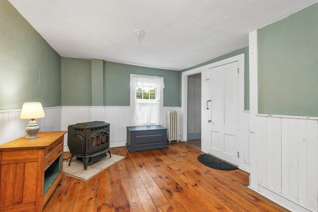 31 Prospect St, Franklin, NH 03235 - foyer featuring radiator heating unit, wainscoting, wood-type flooring, and a wood stove