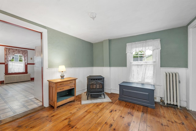 31 Prospect St, Franklin, NH 03235 - sitting room featuring radiator, a wood stove, a wainscoted wall, and plenty of natural light