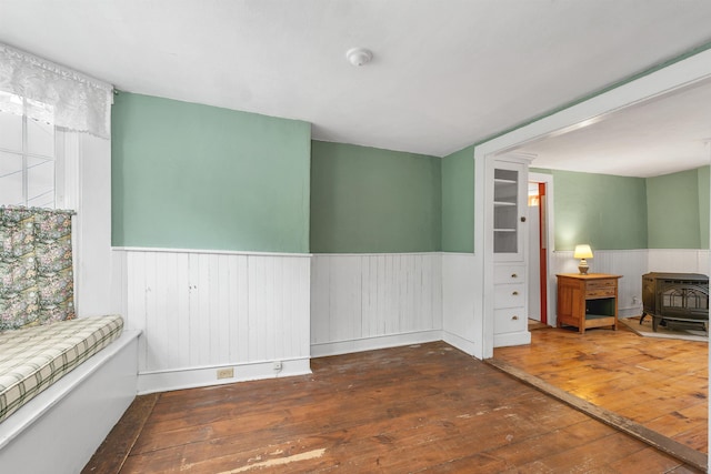 31 Prospect St, Franklin, NH 03235 - unfurnished room featuring a wainscoted wall, a wood stove, and hardwood / wood-style flooring