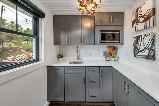 556 Weirs Blvd Unit 4, Laconia, NH 03246 - kitchen featuring a sink, gray cabinetry, light countertops, stainless steel microwave, and tasteful backsplash