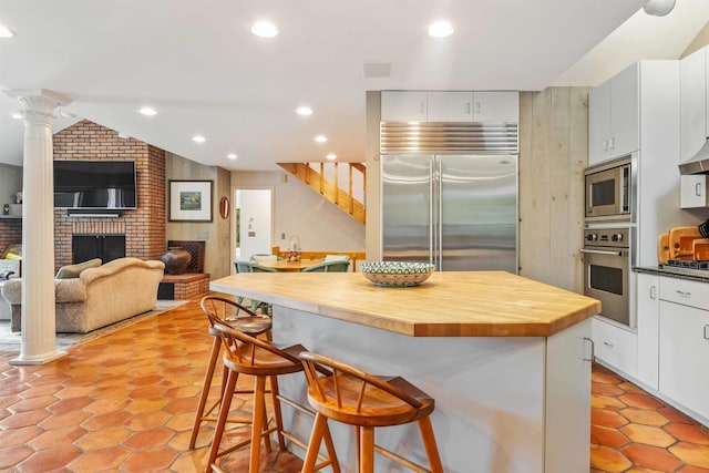 75 Westwood Rd, Sunapee, NH 03782 - kitchen with built in appliances, butcher block counters, a breakfast bar area, white cabinets, and recessed lighting